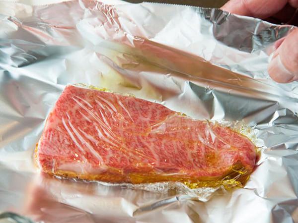 肉にオイルをかけて冷凍する準備をしているイメージ