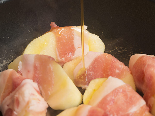 りんごの豚肉巻きソテーのレシピ、オリーブオイルを回しかけた調理中のりんごの豚肉巻き