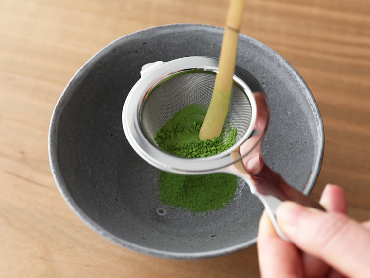茶杓を使って茶漉しで抹茶を漉す様子