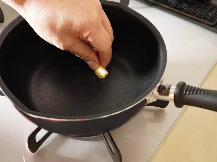 フライパンににんにくをこすりつける様子